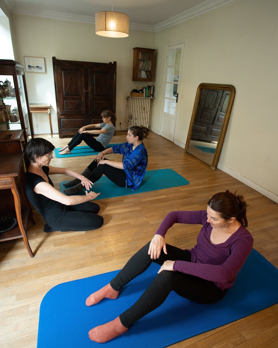 Trois élèves sur leurs tapis, Hélène assise parmi eux.